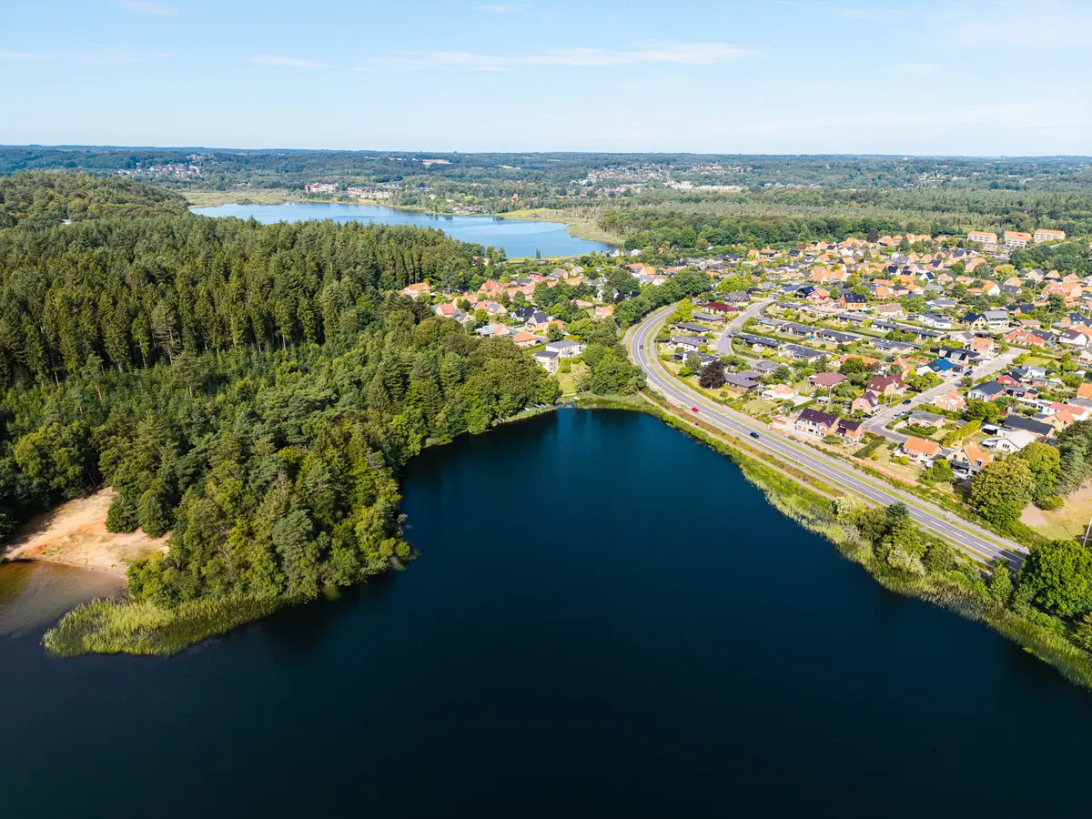 Luftfoto af sø, skov og by