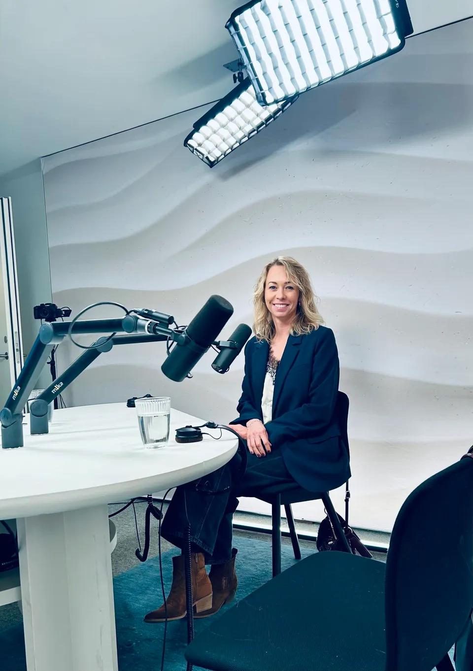 Kvinde sidder ved podcast bord med mikrofoner