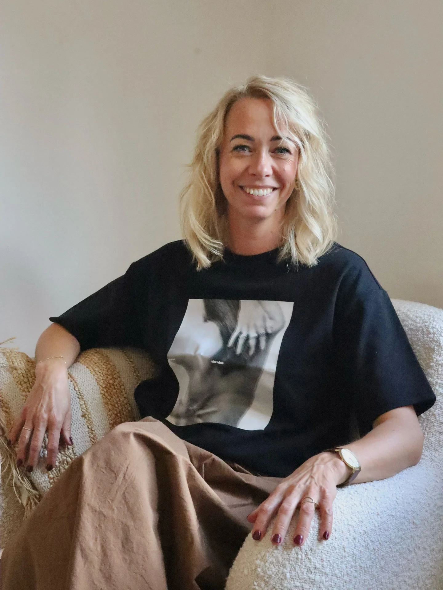 Kvinde smiler og sidder i en stol
