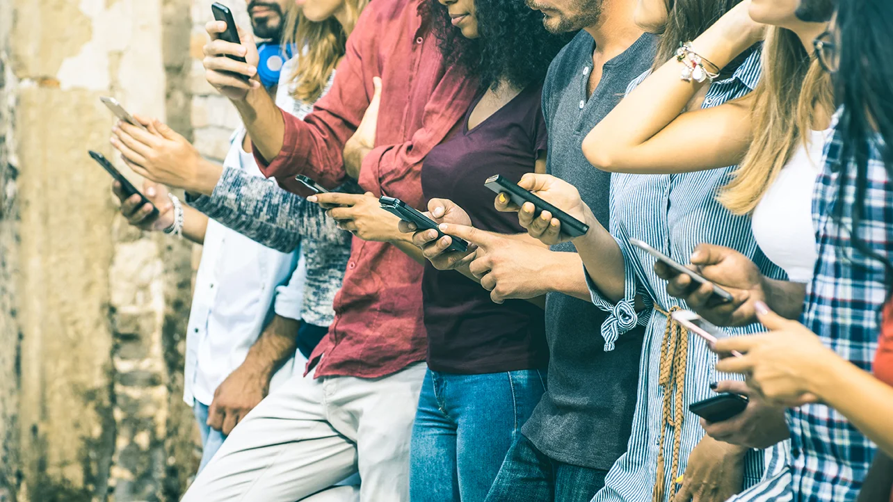 Unge mennesker bruger smartphones sammen udenfor.